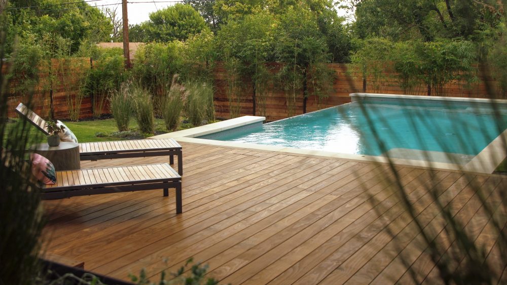 Pool area with deep brown wood deck and seatings.