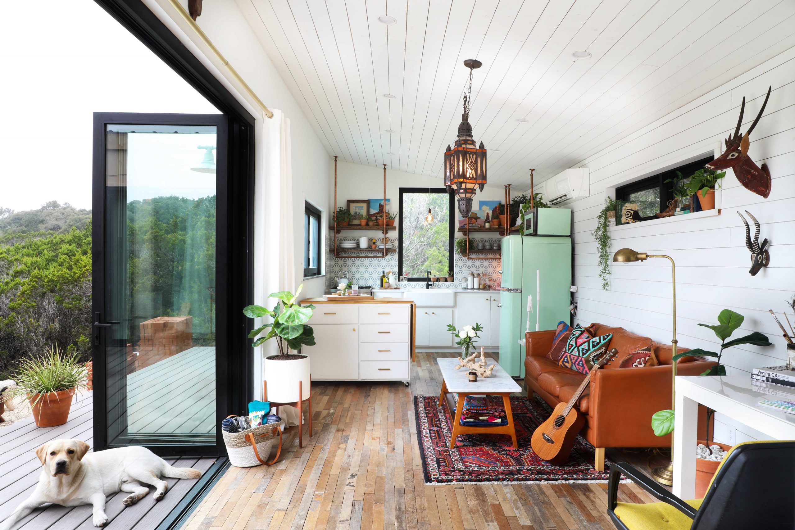 Tiny house with big open window and wooden terrace.