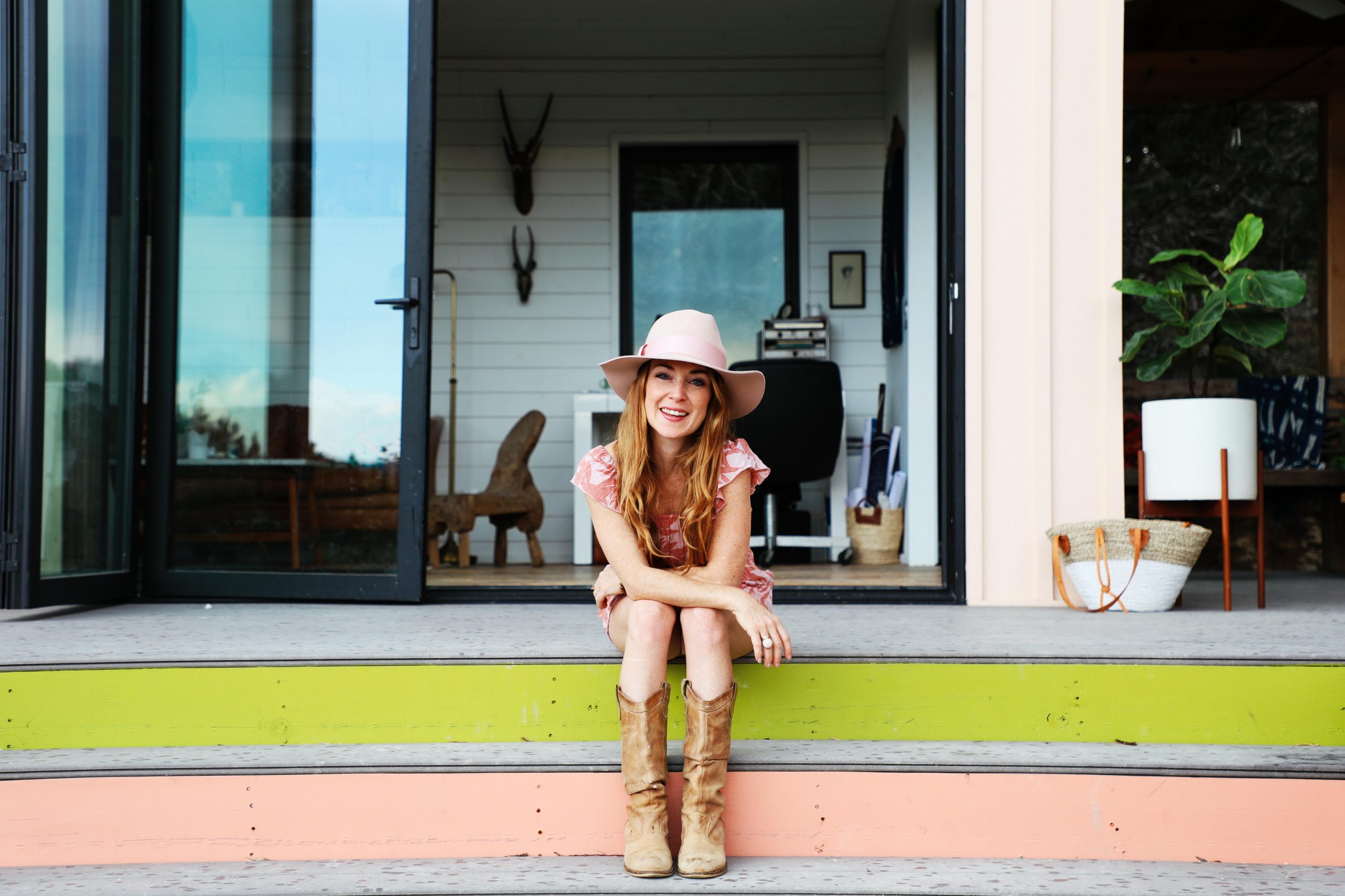 Woman sits on colorful steps in front of her tiny house.